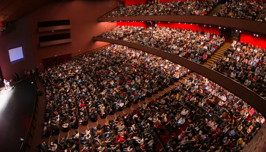 Auditório lotado durante evento empresarial de alto nível